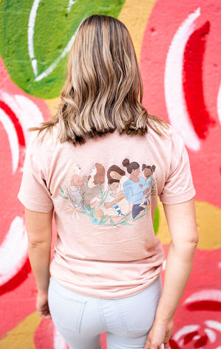 Woman wearing prism peach t-shirt with image of multicultural mothers with children on back . Front of shirt says 'better together' in black text with flowers 